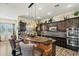 Open kitchen with island featuring stone accents, granite counters, dark wood cabinets, and stainless appliances at 891 W Palo Brea Dr, Litchfield Park, AZ 85340