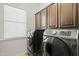 Laundry room features a gray washer and dryer beneath storage cabinets and a window at 891 W Palo Brea Dr, Litchfield Park, AZ 85340