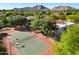 Aerial view of a well-maintained tennis court surrounded by mature trees and mountain views at 9901 N 51St Pl, Paradise Valley, AZ 85253