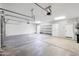 Spacious two-car garage with concrete flooring, overhead lighting, built-in white cabinets, and a side entrance door at 10449 E Lomita Ave, Mesa, AZ 85209