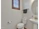 Cozy half bathroom with pedestal sink and brown wood shuttered window at 1052 W Capulin Trl, San Tan Valley, AZ 85140