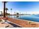 Scenic view of a community lake, featuring a walking path, red rock landscaping, benches and tall palm trees at 10846 W Crosby Dr, Sun City, AZ 85351