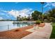 Scenic view of a waterfront area with a dock, a bench, and lush landscaping under a bright sky at 10846 W Crosby Dr, Sun City, AZ 85351