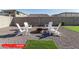 Cozy backyard setup with four Adirondack chairs around a fire pit, bordered by gravel and artificial turf at 11679 W Parkway Ln, Avondale, AZ 85323