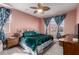 Stylish bedroom with a statement ceiling fan, large bed with decorative pillows, and tropical themed curtains at 11679 W Parkway Ln, Avondale, AZ 85323