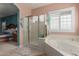 Bright bathroom featuring a large tub, a glass enclosed shower, and a window with wooden shutters at 12443 W Monte Vista Rd, Avondale, AZ 85323