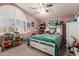 Comfortable bedroom featuring a large window, a bed with a green cover, and a ceiling fan at 12443 W Monte Vista Rd, Avondale, AZ 85323