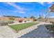 Landscaped backyard with an artificial grass rectangle, gravel, and mature shrubs create a serene outdoor space at 14612 W Edgemont Ave, Goodyear, AZ 85395