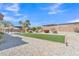 Well-kept backyard has an artificial lawn, desert landscaping, gravel, palm trees, and a charming pergola at 14612 W Edgemont Ave, Goodyear, AZ 85395