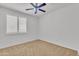 A bright bedroom with carpet, white plantation shutters, and a ceiling fan at 14612 W Edgemont Ave, Goodyear, AZ 85395