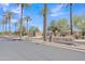 Street view of Paseo Verde entrance showcases well-maintained landscaping and palm trees, welcoming residents at 14612 W Edgemont Ave, Goodyear, AZ 85395