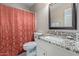 Bathroom with a toilet, single sink, and a shower with a patterned red curtain at 15479 W Whitton Ave, Goodyear, AZ 85395