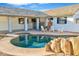 Outdoor pool area with a rock waterfall feature, white lounge chairs, and covered patio at 16029 N 36Th Dr, Phoenix, AZ 85053