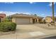 Charming home with a two-car garage, desert landscaping, and a lush green bush by the driveway at 16051 W Desert Winds Dr, Surprise, AZ 85374