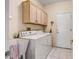 Bright laundry room featuring a white washer and dryer with overhead cabinets at 16051 W Desert Winds Dr, Surprise, AZ 85374