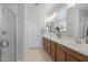 Bright bathroom featuring double sinks with warm wood cabinets and a glass-enclosed shower at 1677 E Bridgeport Pkwy, Gilbert, AZ 85295