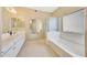 Bright bathroom with white cabinets, a large mirror, a bathtub, and a glass-enclosed shower at 17036 N 43Rd Pl, Phoenix, AZ 85032