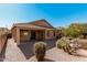 An open backyard showing the back of the house, a covered patio, and desert landscaping at 17642 W Pershing St, Surprise, AZ 85388