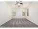 Spacious bedroom featuring neutral carpet, a ceiling fan, two large windows, and natural light at 17642 W Pershing St, Surprise, AZ 85388