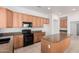 Kitchen featuring granite countertops, black appliances, tile flooring, a center island, and wood cabinets at 17642 W Pershing St, Surprise, AZ 85388