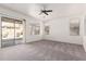 Spacious living room with neutral carpet, a ceiling fan, and a sliding glass door to the patio at 17642 W Pershing St, Surprise, AZ 85388