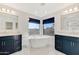 Luxurious bathroom features dual vanities, modern fixtures, a freestanding tub, and large windows with blue shades at 21915 N 65Th Ave, Glendale, AZ 85310