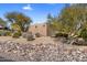 Exterior view of the property showcasing desert landscaping with rocks and mature trees at 25621 N Cordova Ln, Rio Verde, AZ 85263