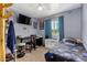 Bedroom with light gray walls, ceiling fan, window, and a mounted TV with a desk at 2848 E Brown Rd # 30, Mesa, AZ 85213