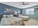 Bedroom with two beds, ceiling fan, and neutral carpet, featuring a blue accent wall at 29740 W Fairmount Ave, Buckeye, AZ 85396