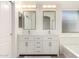 Bathroom featuring double sinks, framed mirrors, tub and shower combo, and modern lighting at 3034 E Coconino Dr, Gilbert, AZ 85298