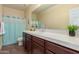 Well-lit bathroom with a dark wood vanity, and a white tile countertop with a bright aqua shower curtain at 30488 N 126Th Dr, Peoria, AZ 85383