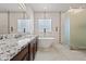 Sleek bathroom features dual sinks with granite countertops, a freestanding tub, and a frosted glass shower at 30488 N 126Th Dr, Peoria, AZ 85383