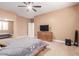 Cozy bedroom features ceiling fan, neutral color scheme and dresser with a flatscreen TV at 30488 N 126Th Dr, Peoria, AZ 85383