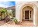 Elegant front entrance featuring an arched doorway, wood door, and lush landscaping at 30488 N 126Th Dr, Peoria, AZ 85383