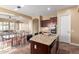 Kitchen island with dark cabinets, granite countertops, and stainless steel appliances adjacent to a dining area at 30488 N 126Th Dr, Peoria, AZ 85383