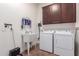 Functional laundry room features a utility sink, washer, dryer, and storage cabinets for efficient organization at 30488 N 126Th Dr, Peoria, AZ 85383