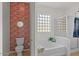 Well-lit bathroom with a tub/shower combo and decorative brick accent wall at 3746 E Vallejo Dr, Gilbert, AZ 85298