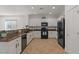 Modern kitchen with white cabinets, black appliances, granite countertops, and tile flooring at 3746 E Vallejo Dr, Gilbert, AZ 85298