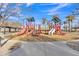 Community playground featuring slides, climbing structures and seating, with views of swaying palm trees at 3906 N 297Th Cir, Buckeye, AZ 85396