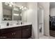 Bathroom featuring a double vanity with dark wood cabinets, a large mirror, and a separate toilet room at 3923 S 244Th Dr, Buckeye, AZ 85326