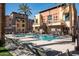 Community pool with lounge chairs, palm trees, and luxurious condos on a bright, sunny day at 4931 N Woodmere Fairway -- # 1001, Scottsdale, AZ 85251