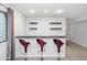 Basement bar with three red bar stools, shelving, and a window, ideal for entertaining at 5507 E Shea Blvd, Scottsdale, AZ 85254