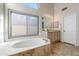 Bright bathroom featuring a soaking tub, a vanity, and a large window offering plenty of natural light at 5507 E Shea Blvd, Scottsdale, AZ 85254