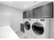 Well-equipped laundry room featuring front loading washer and dryer and ample storage cabinetry at 5507 E Shea Blvd, Scottsdale, AZ 85254