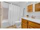 Bathroom featuring a shower-tub combo, toilet, and white sink with wood cabinetry at 6329 E Dodge St, Mesa, AZ 85205