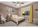 Well-lit bedroom with a metal bed frame, ceiling fan, and yellow curtains at 65 W Cucumber Tree Ave, San Tan Valley, AZ 85140