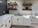 Bright kitchen featuring white cabinetry, marble countertops, floating wood shelves, and modern fixtures at 6532 N 60Th N Ave, Glendale, AZ 85301