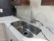 Close-up of the kitchen sink with granite countertop and a modern faucet and black tile accent at 6532 N 60Th N Ave, Glendale, AZ 85301