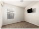 This minimalist bedroom features neutral carpet, a window and a wall-mounted TV at 757 E Lovegrass Dr, San Tan Valley, AZ 85143