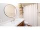 Bathroom featuring a circular mirror, single vanity, wooden shelves, and a shower with a white shower curtain at 824 W Luke Ave, Phoenix, AZ 85013